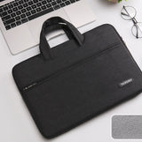Black laptop sleeve with handle on a desk next to a laptop and glasses